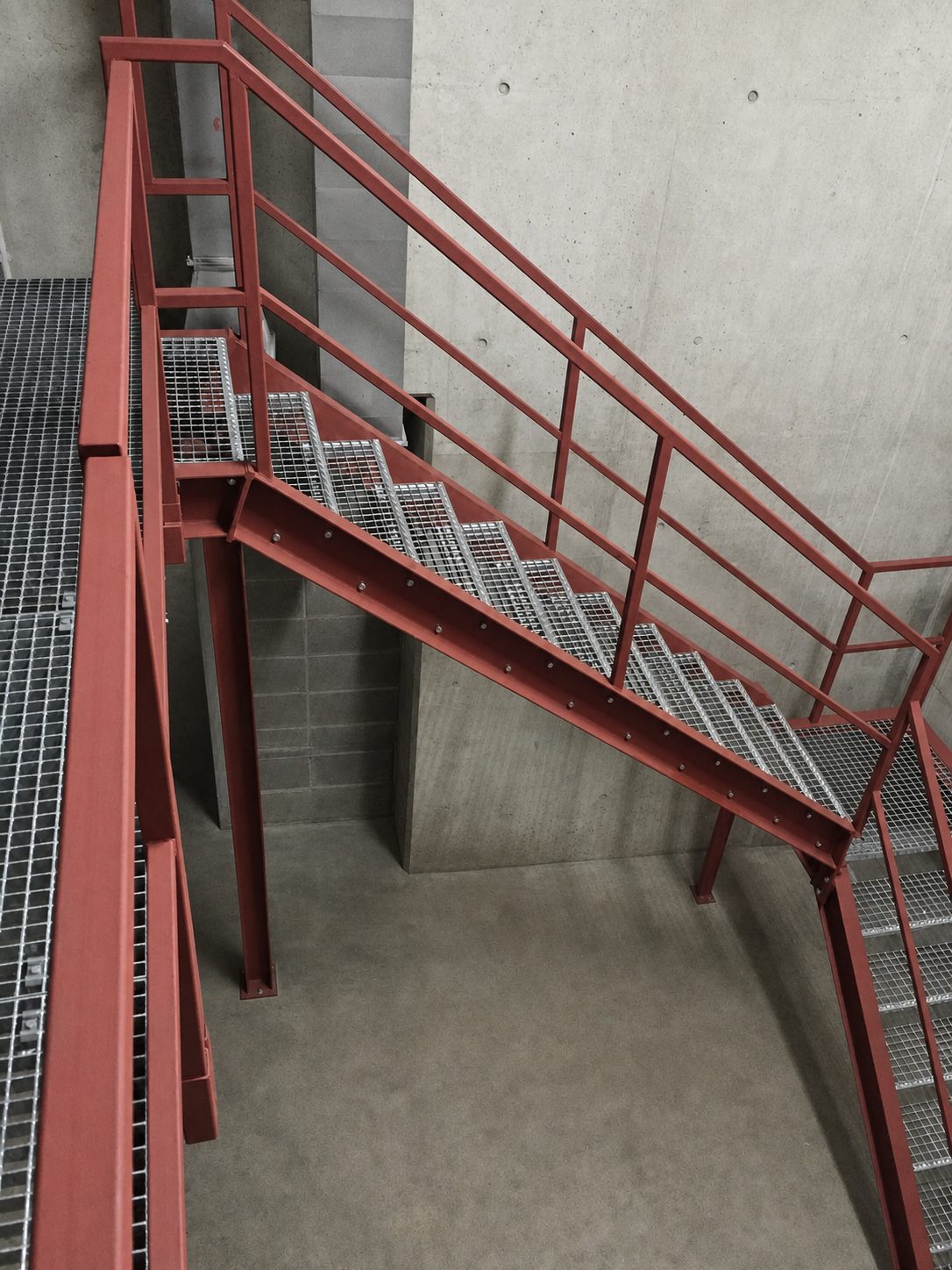 Rot lackierte Stahltreppe mit Gitterroststufen im Innenraum