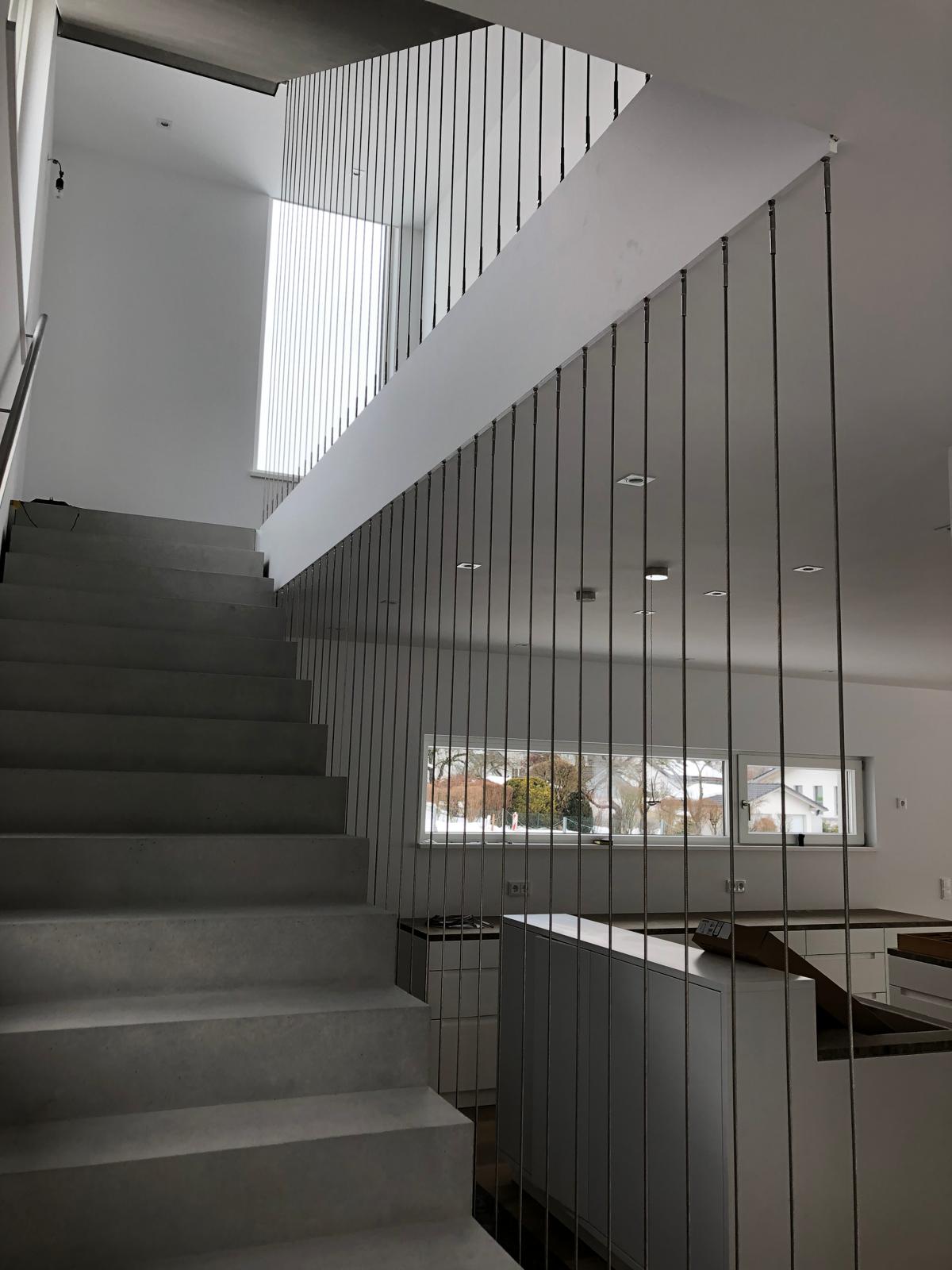 Betontreppe mit Edelstahl-Seilgeländer in einem Wohnhaus